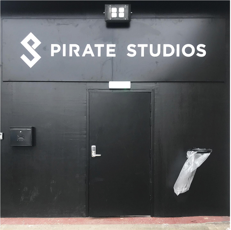 black building with black security door with keypad handle on and pirate studios sign above in white text