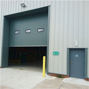 Outside shot of a grey roller shutter with three windows in the middle and a grey security door to the right of it