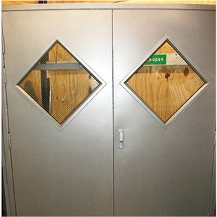 A silver set of steel double doors with diamond vision panels in the middle of each door stood up to a wooden background